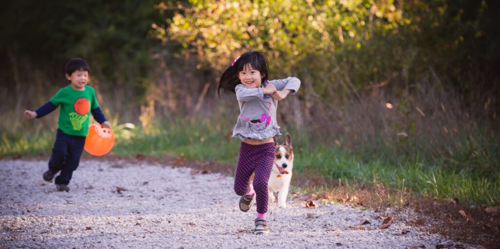 Audrey and Wesley running on a gravel path with their corgi, laughing and mid-stride — a candid family moment photographed by Lai Xu of Bokeh Story Photos