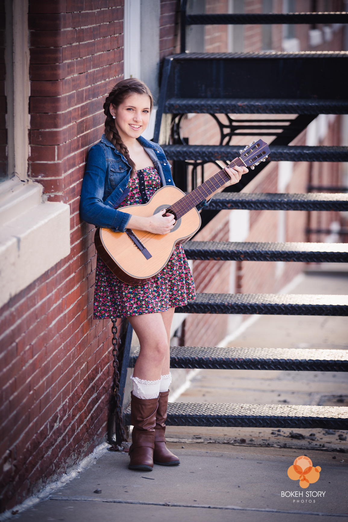 Senior portrait of Catherine with guitar on brick wall fire escape, Kansas City