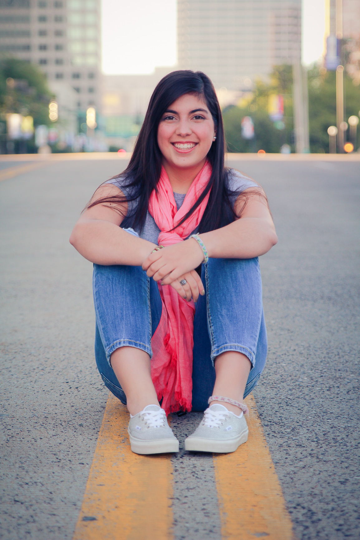 Senior portrait of Nora sitting on downtown Kansas City street centerline at sunrise