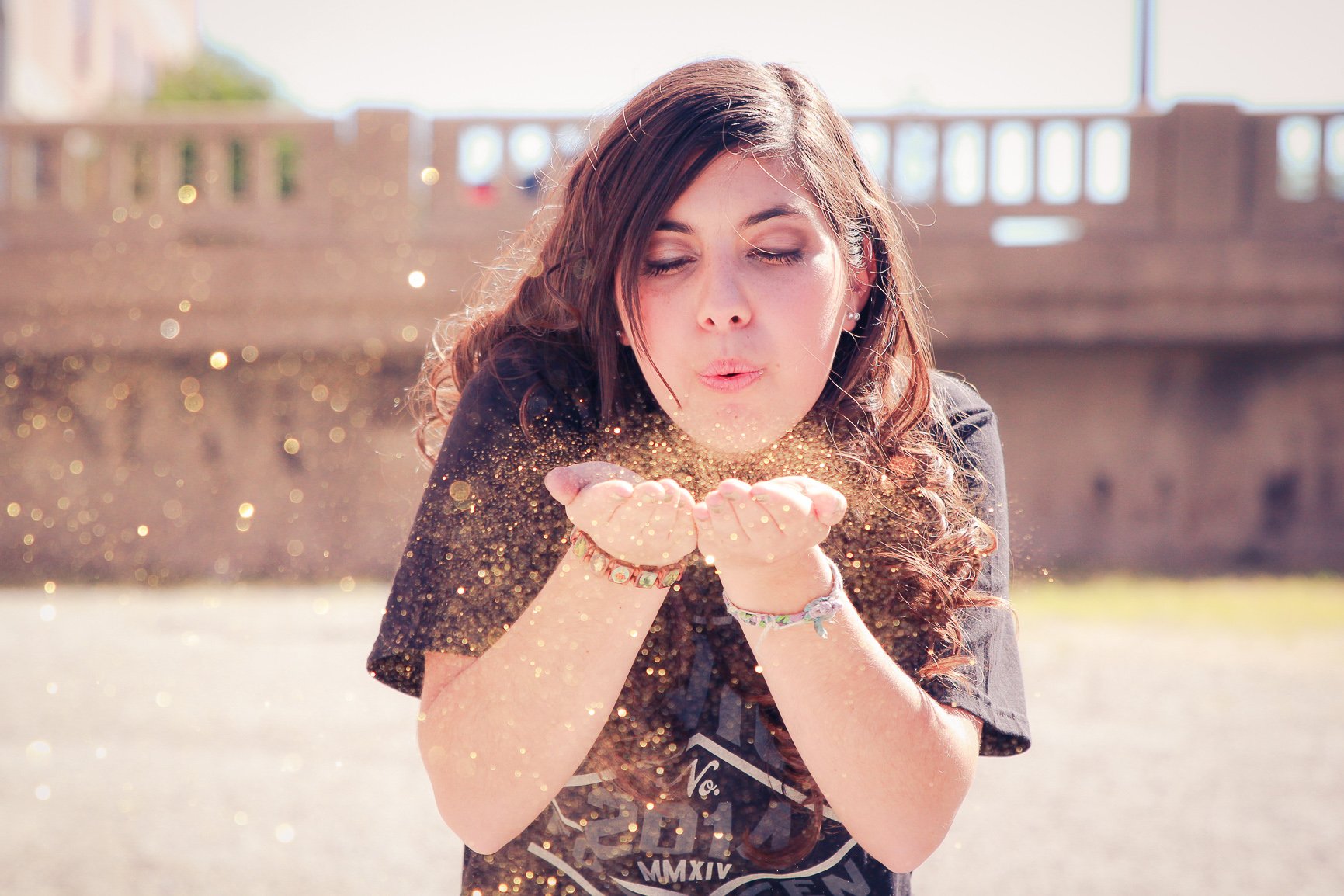 Nora blowing glitter toward the camera during an outdoor senior portrait session.
