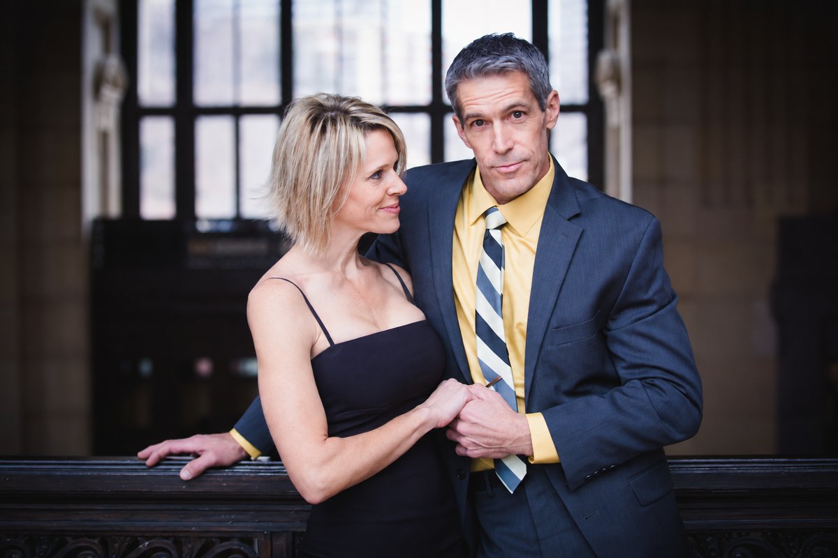 Rick in a navy suit beside an actress in a black dress during a staged date scene for his actor portfolio at Union Station in Kansas City.